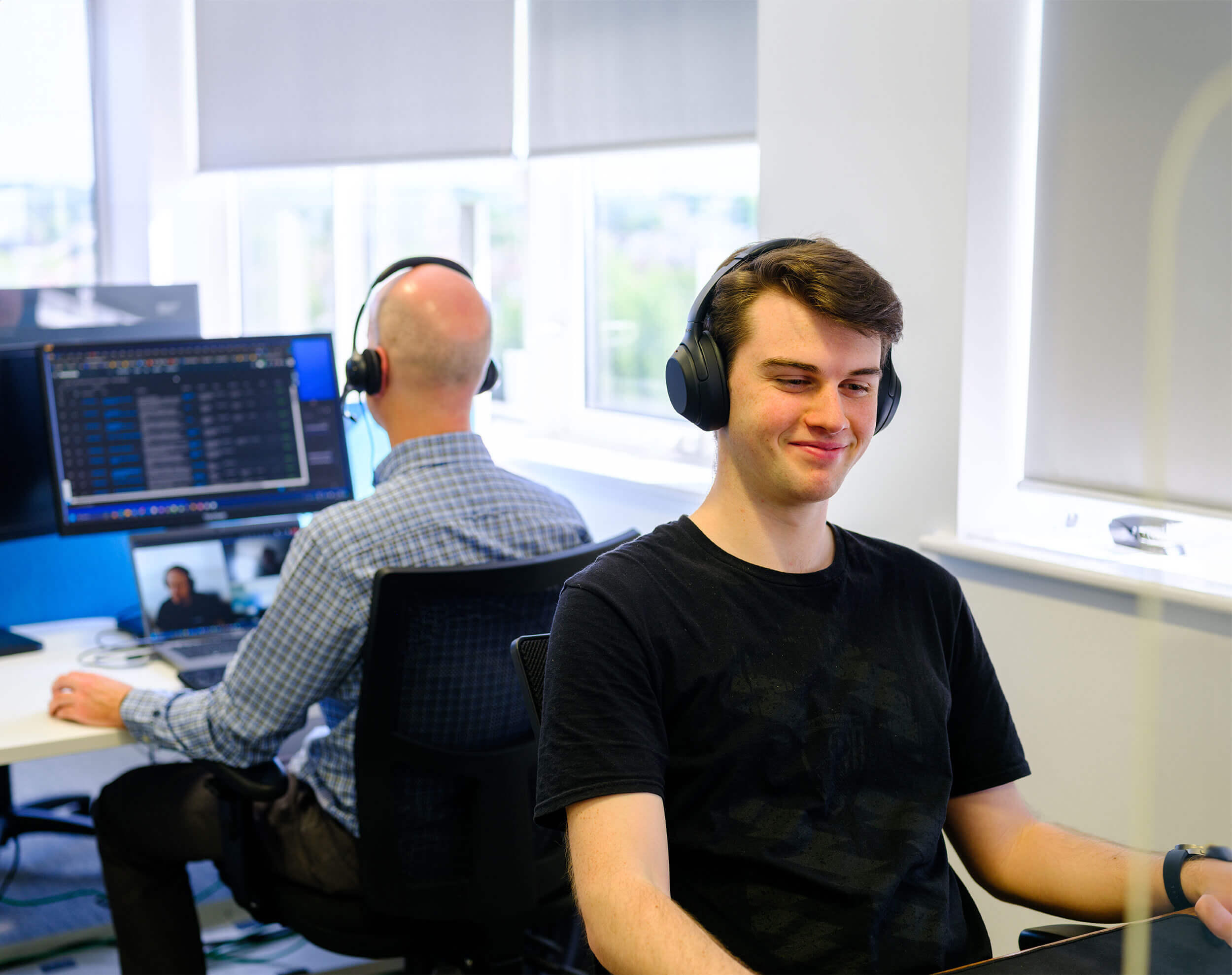 Resolute Cyber team members working at desks with headphones, focused on cybersecurity tasks.